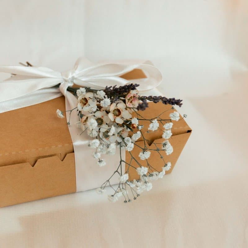 Coffret artisanal fermé d'un ruban blanc et orné de fleurs séchées