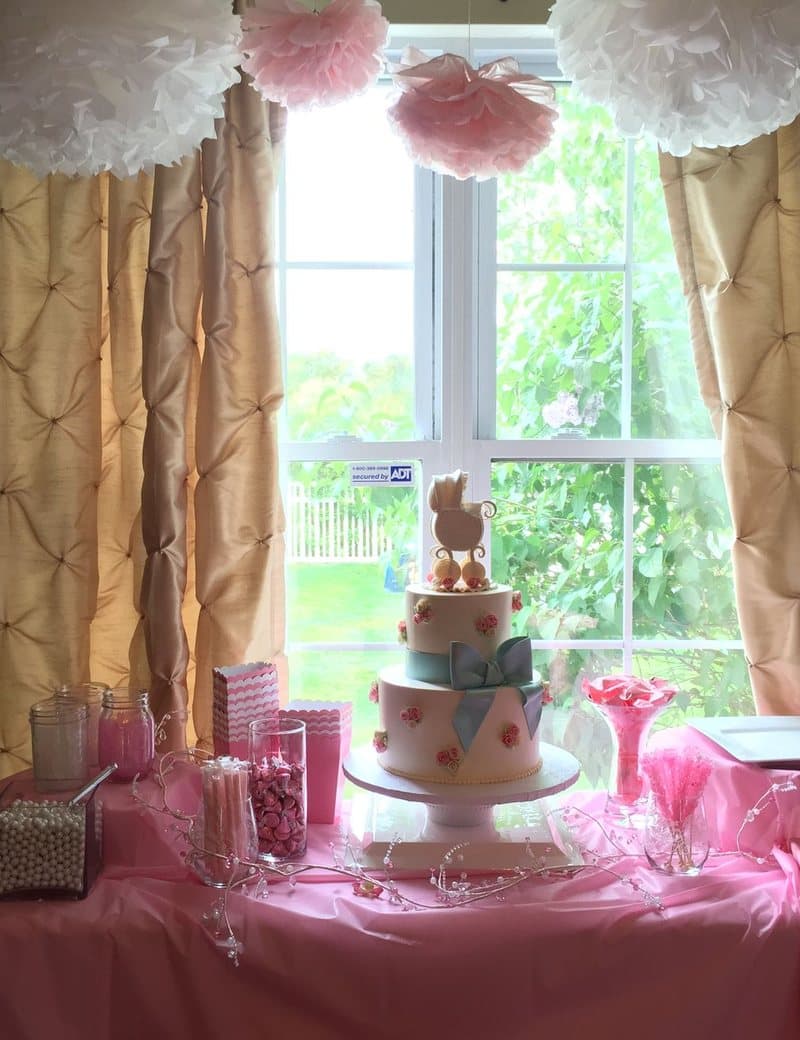 Table de baby shower décorée aux tons roses avec gâteau